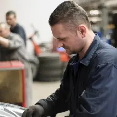 Mechanik w warsztacie naprawia oponę samochodową.