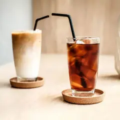 Zwei Gläser mit Eiswürfeln und Strohhalmen. Eines ist ein cremiger Eiskaffee, das andere ein dunkler Kaffee mit kaltem Wasser.