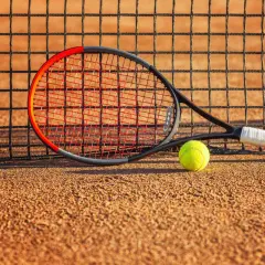 Rakieta tenisowa Wilson Clash i piłka leżą na korcie, gotowe do gry.