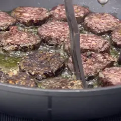 Rodajas de morcilla de Burgos dorándose en sartén con aceite burbujeante. Perfectas para tus recetas.