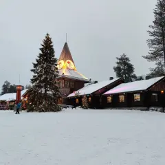 Śnieżny krajobraz z choinką i budynkami, gdzie znajduje się dom Świętego Mikołaja.