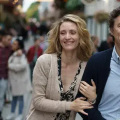 Uśmiechnięta para idzie ulicą, mężczyzna obejmuje kobietę.
