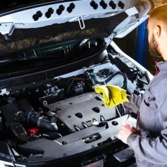 Mechanik sprawdza poziom oleju w silniku. Gdy przyjdzie czas na wymianę, dowiedz się, gdzie oddać zużyty olej silnikowy.
