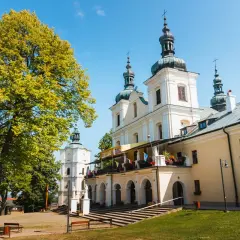 Kalwaria Pacławska: majestatyczna bazylika z wieżami i arkadowym gankiem, otoczona zielenią.
