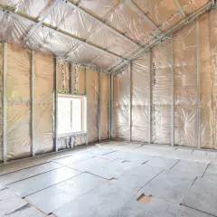 Interno di un sottotetto in fase di isolamento. Pareti e soffitto rivestiti con materiale riflettente e struttura metallica per il cartongesso. Pavimento con pannelli e materiale isolante.