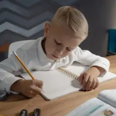 Chłopiec z zapałem uczy się, jak nauczyć dziecko odejmować do 20, pisząc w zeszycie.