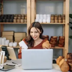 Kobieta prezentuje produkty do swojego sklepu na Facebooku, trzymając w rękach drewniane przedmioty.
