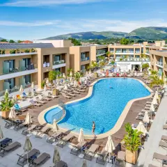 Luksusowy hotel White Olive Elite w Laganas, Grecja. Basen, leżaki i palmy tworzą idealne miejsce na relaks.