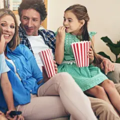 Rodzina ogląda filmy dla dzieci, zajadając popcorn.