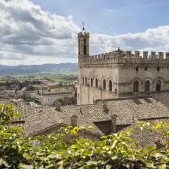 Gubbio da vedere: imponente Palazzo dei Consoli domina il borgo medievale con i suoi tetti in cotto e le colline umbre sullo sfondo.