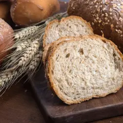 Różnorodne pieczywo, w tym bochenki z ziarnami i kromki chleba pełnoziarnistego. Idealne, gdy zastanawiasz się, jakie pieczywo przy odchudzaniu wybrać.