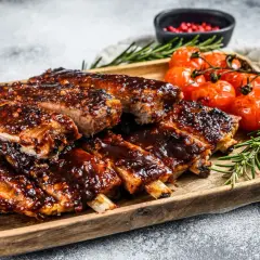 Soczyste żeberka w sosie BBQ, podane z pieczonymi pomidorkami i rozmarynem. Idealne na obiad lub grilla.