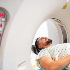 Mężczyzna leży w aparacie do rezonansu jamy brzusznej, przygotowując się do badania.