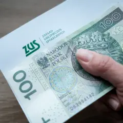 Dłoń trzyma banknot 100 zł i dokument ZUS. Może to symbolizować wsparcie finansowe, np. renta na depresję.
