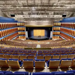 El **palacio de festivales** luce vacío, con sus butacas azules y doradas listas para recibir al público. Un piano espera en el escenario.