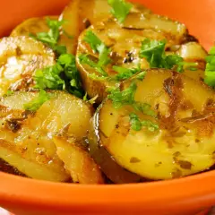 Gegrillte Schmorgurken mit Speck, garniert mit Petersilie, in einer orangen Schale.