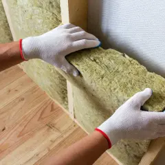 Pose d'isolant dans une structure de mur en bois. L'isolation aide à prévenir l'humidité du mur et améliore le confort thermique.