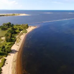 Malowniczy deptak na wyspie Sobieszewskiej prowadzi przez wodę do piaszczystej ławicy.