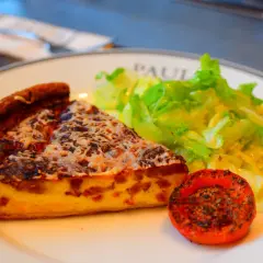 Kawałek quiche lorraine, sałatka i pieczony pomidor – klasyka kuchni francuskiej.
