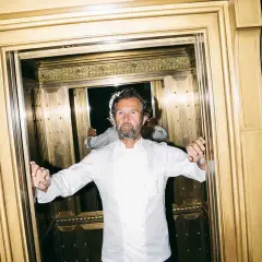 Lo chef Cracco, con la sua giacca bianca, in un ascensore dorato. Quante stelle Michelin ha Cracco?
