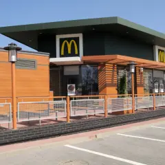 Nowoczesny McDonald's z drewnianymi elementami i dużymi oknami. Idealne miejsce na szybki posiłek, może nawet na słynne krewetki McDonald's, jeśli będą dostępne.