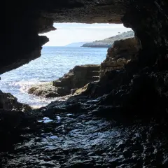 Vista dall'interno di una grotta sul mare cristallino e la costa rocciosa. La spiaggia della grotta verde è un luogo magico.