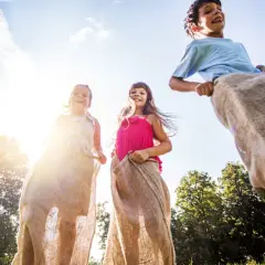 Barn hoppar säcklöpning i solen. Perfekt för tips på femkamp eller en rolig sommardag!