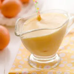 Crema pastelera cremosa en una salsera de cristal, con huevos frescos al fondo. Perfecta para rellenar postres.