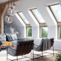 Przytulny salon pod skosem z oknami dachowymi, przez które wpada światło. Wygodne fotele i sofa zapraszają do relaksu.