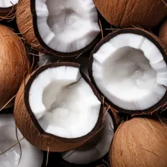 Cocos frescos, algunos enteros y otros partidos, revelan su pulpa blanca y cremosa. Un festín visual que evoca las múltiples propiedades del coco.