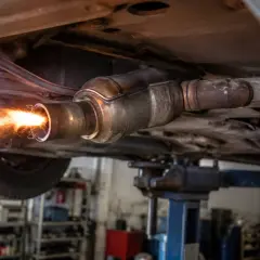 Ogień i iskry wydobywają się z rury wydechowej samochodu na podnośniku. To proces wypalania DPF.