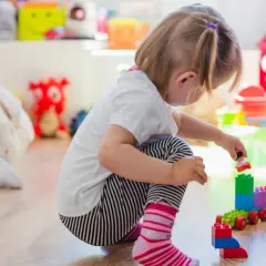 Niña jugando con bloques, concentrada en su mundo, un ejemplo de egocentrismo infantil.