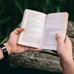 Ręce trzymają otwartą książkę z tekstem. To może być jedna z **książek sensacyjnych top 10**, idealna na relaksujący wieczór.
