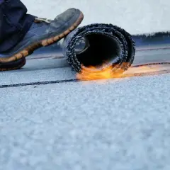 Dachdecker macht Dachpappe begehbar, indem er sie mit einem Brenner verschweißt.