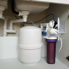 Système de filtration d'eau sous évier, incluant un réservoir blanc et un filtre violet, pour une purification par **osmose inverse**.