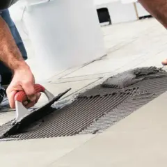 Uomo con spatola stende colla per piastrelle bagno fai da te. Nuove piastrelle in posa.