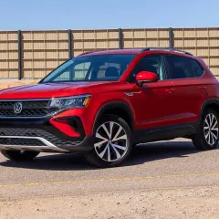 Czerwony Volkswagen Taos stoi na drodze, z tyłu widać betonowe ogrodzenie.