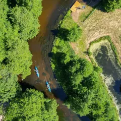 Dwie kajaki płyną rzeką wśród zieleni, malowniczy krajobraz Kociewia w okolicach Starogardu Gdańskiego.