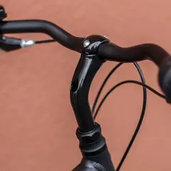 Czarne kierownica i mostek roweru, widoczne śruby mocujące. Chwila przed dokręceniem śrub w rowerze.