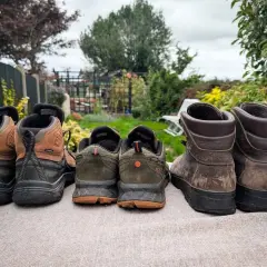 Choosing hiking boots: A selection of hiking boots and shoes, from lighter trail runners to sturdy leather boots, are lined up outdoors.