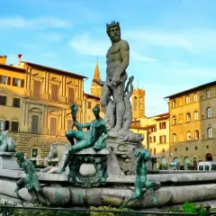 La Fontana del Nettuno a Firenze, con le sue sculture in bronzo e marmo, domina la piazza sotto un cielo azzurro.