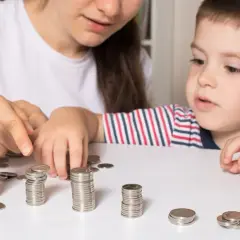 Mama z synkiem liczą monety, planując wydatki na dziecko. Zasiłek opiekuńczy na dziecko może pomóc w takich sytuacjach.