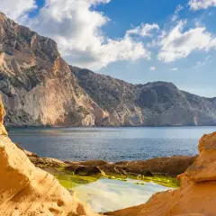 Acantilados dorados y mar azul en Ibiza, un rincón que evoca la magia de Atlantis Ibiza.
