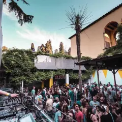 DJ set su una terrazza a Barcellona, con folla che balla sotto il cielo azzurro.