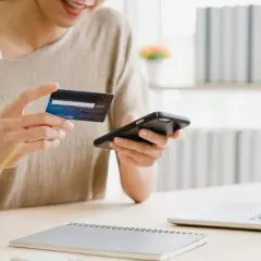 Kobieta płaci kartą przez telefon, korzystając z integracji **PayPal WooCommerce** do zakupów online.