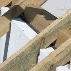 Drewniana konstrukcja dachu z belkami i murłatą opiera się na białych bloczkach z betonu komórkowego.