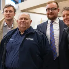 Grupa osób, w tym policjant, pozuje do zdjęcia. Wyglądają, jakby reżyser u pana boga za piecem ustawił ich do tej sceny.