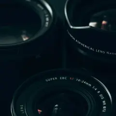 Three Fujifilm lenses, including the XF 10-24mm, are arranged for a street photography shoot.