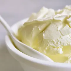 Kremowa masa w białej miseczce z łyżką. Szukasz, czym zastąpić mascarpone? Oto puszysta alternatywa.