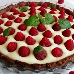 Tarta z mascarpone i białą czekoladą, ozdobiona malinami i miętą. Kwestia smaku, która zachwyca!